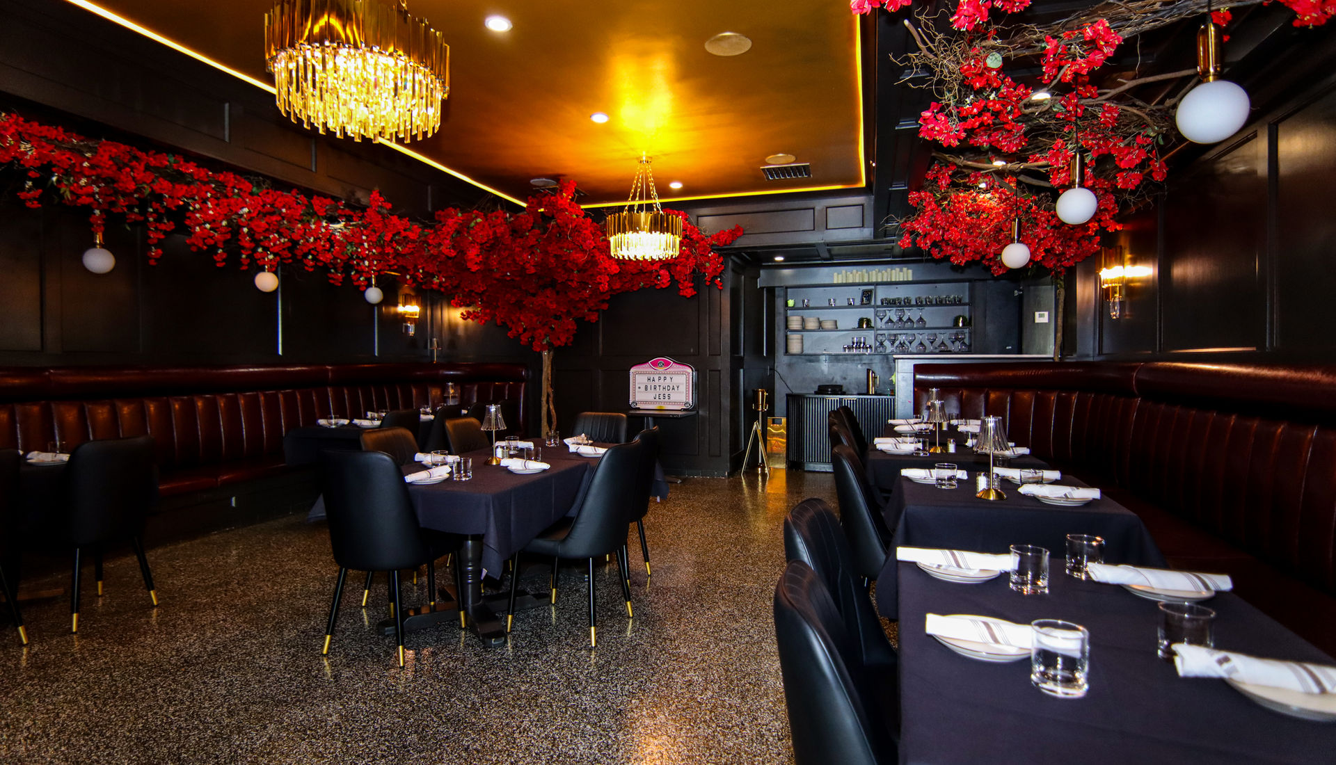 Elegantly set Fuego Steakhouse & Bar dining room with red florals and gold chandeliers