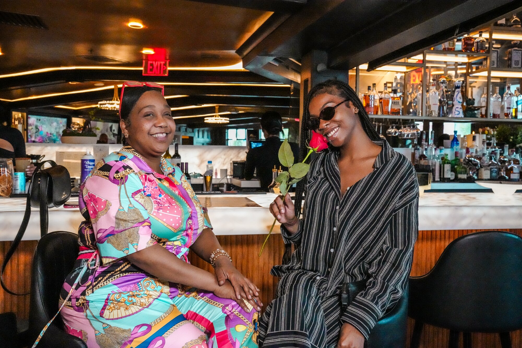 Friends sharing a rose and a laugh at the bar