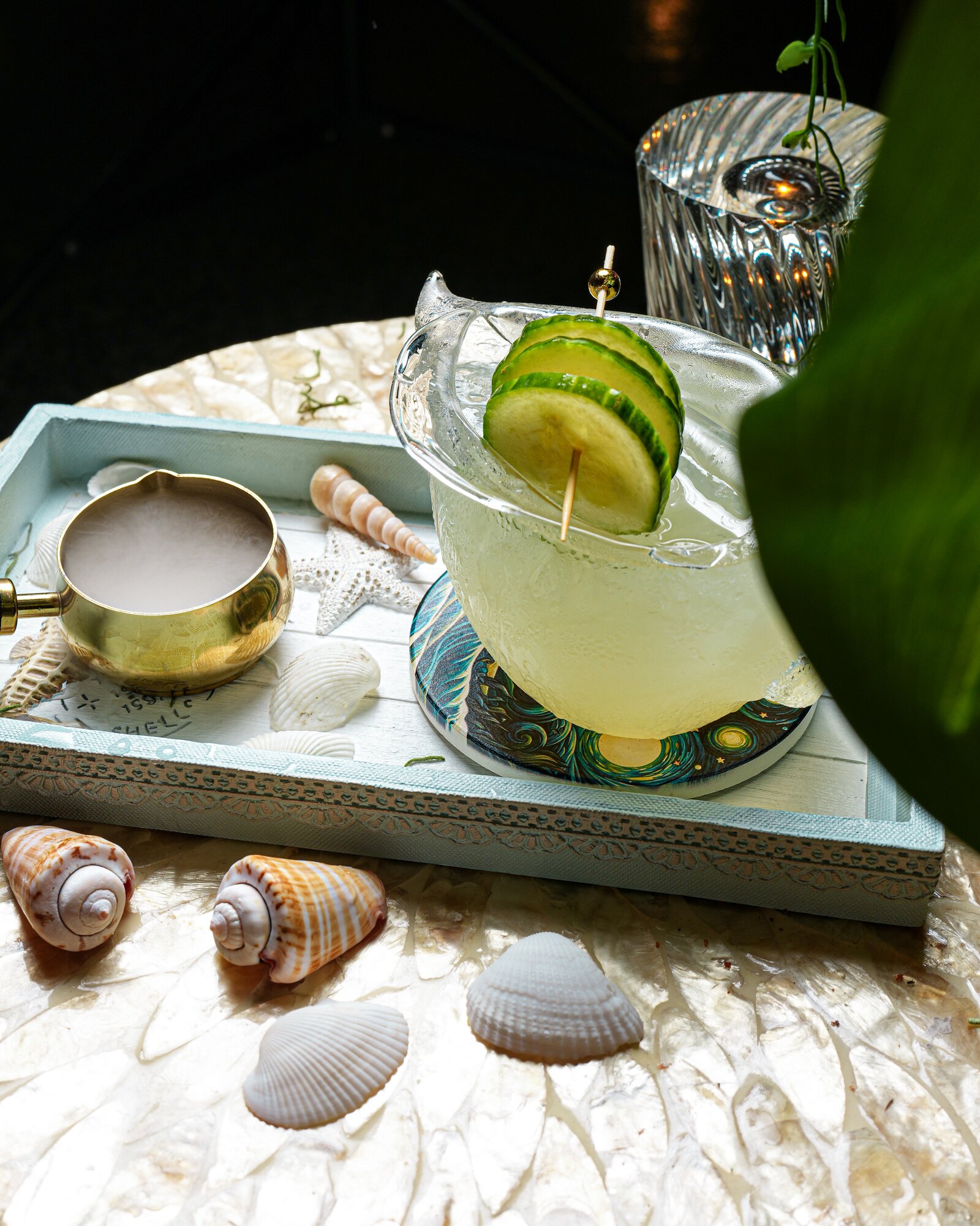 A cucumber cocktail with dry-ice smoke on a seashell tray
