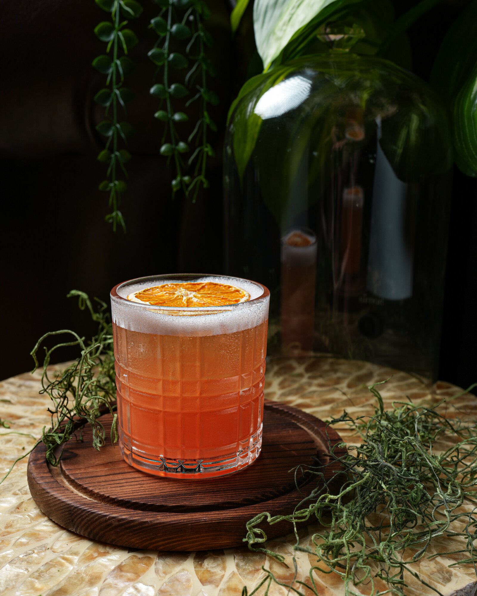 An amber whiskey sour topped with a dried orange wheel