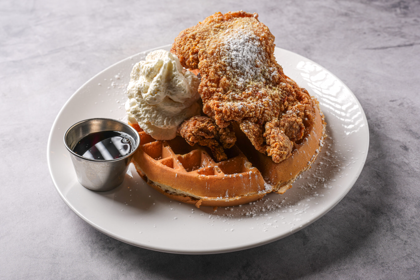 Chicken & waffles with a dusting of powdered sugar and maple syrup